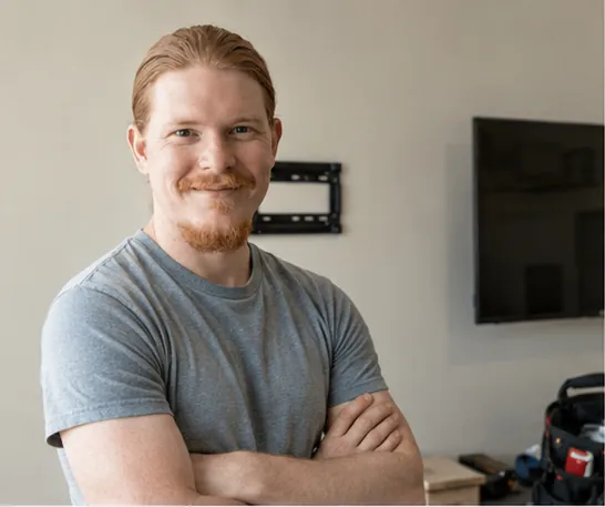 Rusty standing near a mounted TV before the final check